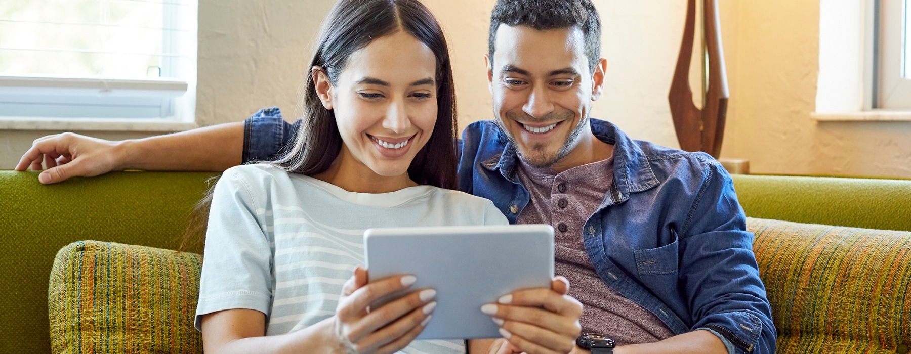 Couple sitting in their living room on a tablet 